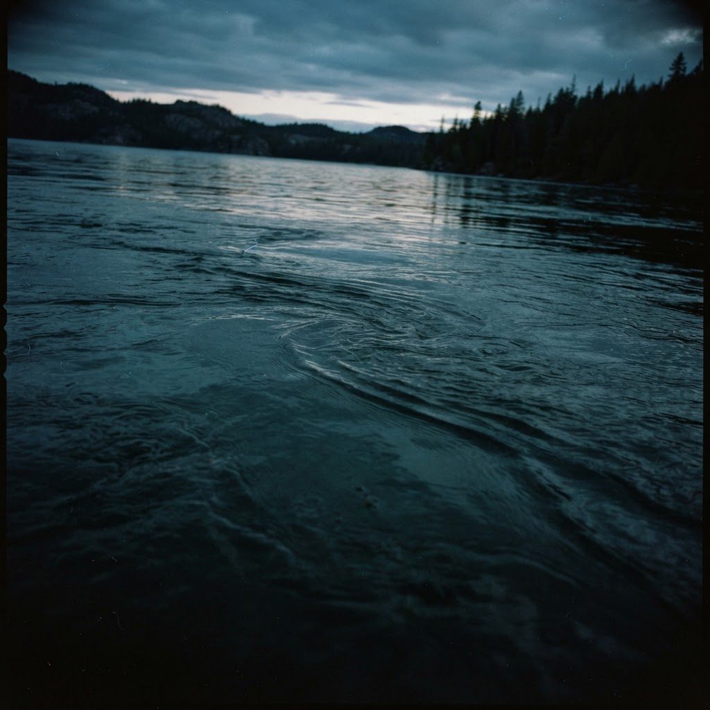 Smooth current lines moving across the surface of a dark lake at dusk
